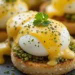 A close-up of perfectly poached eggs on English muffins with hollandaise sauce and a sprinkle of parsley