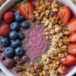 A vibrant smoothie bowl topped with fresh fruits, granola, and chia seeds